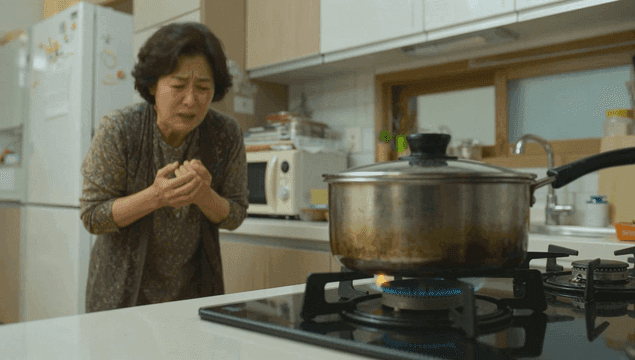 주방에서 끓는 냄비 옆에서 화상으로 고통스러워하는 노인 여성