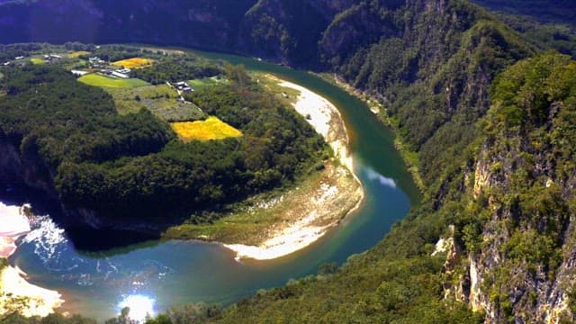 Meandering river through a lush forest valley on a sunny day