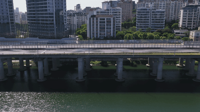 Bridges with cars speeding over river and city apartments