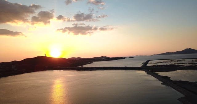 Sunset over a calm sea with distant mountains