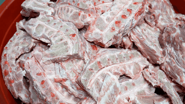 Raw pork neck bone pieces in red container