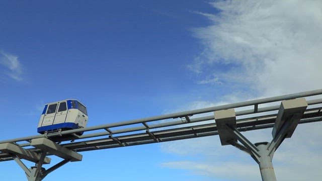 Monorail gliding on track against a blue sky