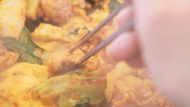 Chopsticks picking up spicy dakgalbi with vegetables