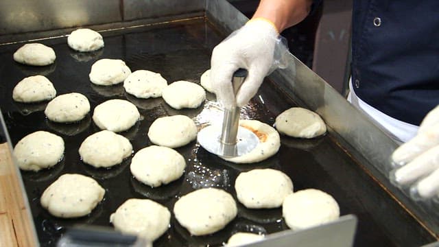 Dough of Korean hotteok being pressed on a griddle