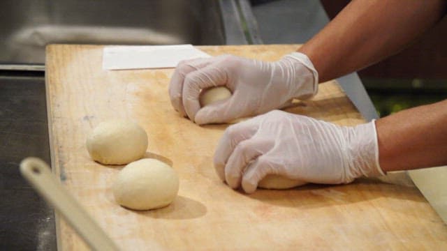 Hands kneading dough on a wooden board