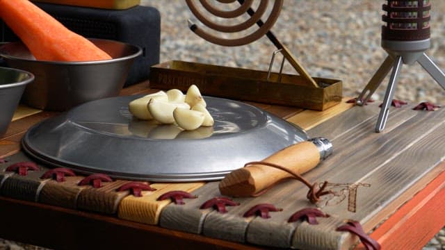 Chopping garlic with a small knife on a wooden table