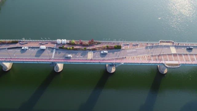 고요한 강 위의 다리를 달리는 자동차들