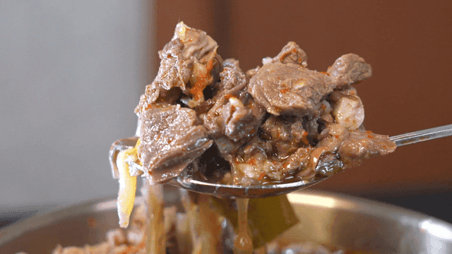 Serving spicy steaming beef soup with spoon