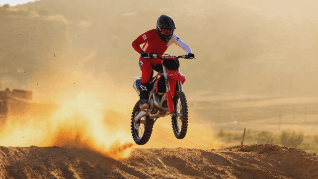 Person riding motorcycle on sand track.
