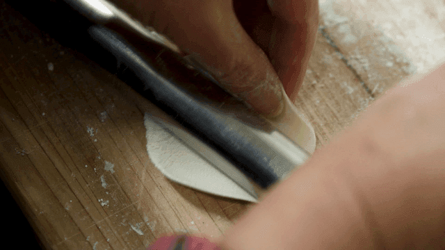 Hand rolling dough on floured wooden cutting board