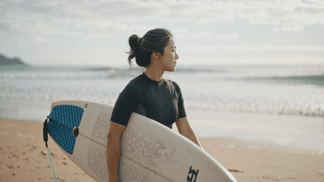 Woman holding surfboard on beach