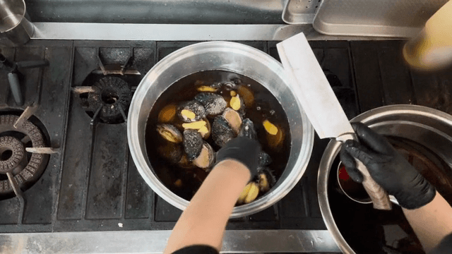 전복이 있는 냄비에 생강을 넣는 손