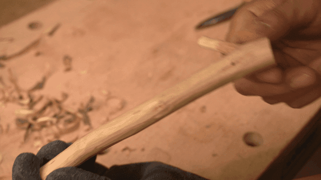 조각된 나뭇가지를 검사하는 손