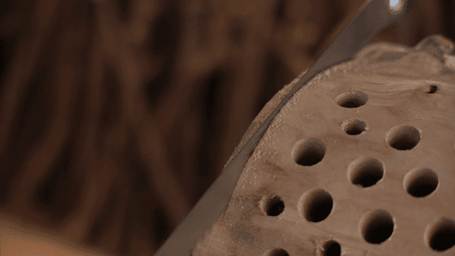 많은 구멍이 나있는 나무를 자르는 긴 톱