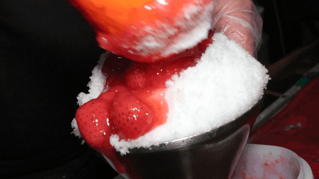빙수 위에 딸기 시럽을 붓는 장면