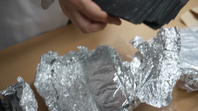 실험실에서 검은 종이 샘플을 다루고 있는 과학자