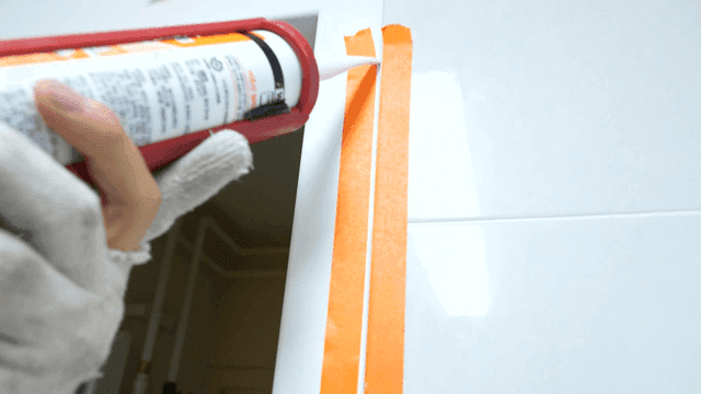 욕실 타일 벽에 마스킹 테이프 사이로 발려지는 실란트