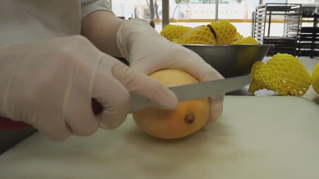 Skillfully preparing a mango by peeling and slicing it