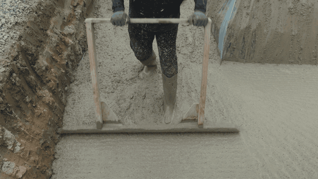 Worker smoothing wet concrete with a tool