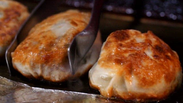 Crispy dumplings frying in a pan