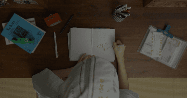 빨간 글씨로 공책에 글을 쓰는 사람