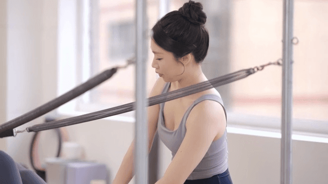 Pilates instructor assists a student indoors