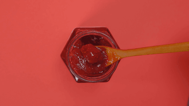 Jar of strawberry jam with a spoon