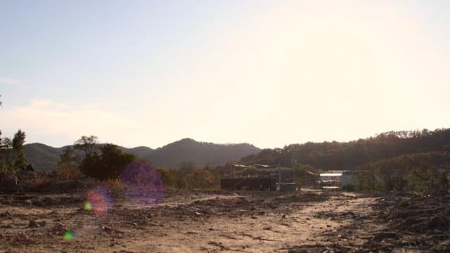 해 뜰 무렵 흙길을 따라 여행용 가방을 끌고 가는 사람