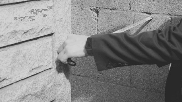 벽을 줄자로 측정하는 사람