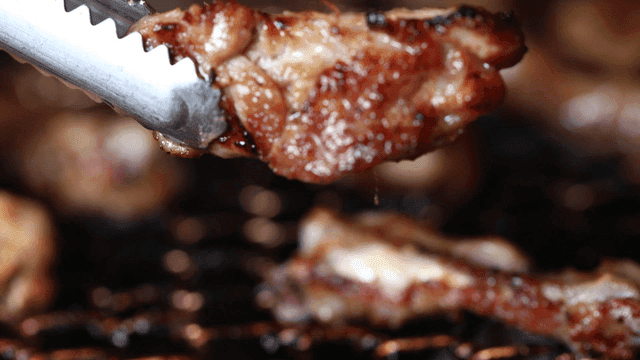 Chicken on grill lifted with tongs