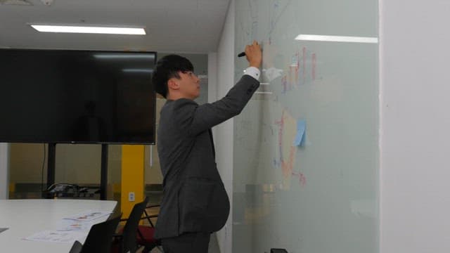 사무실에서 화이트보드에 글을 쓰는 남자
