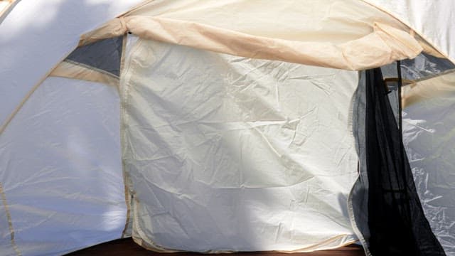 녹음을 배경으로 설치된 텐트의 문을 여는 모습