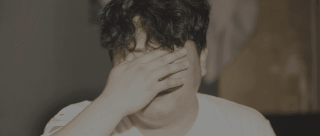 Man in a white shirt squinting in the morning sunlight