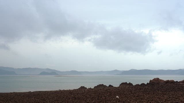 Rocky beach on a cloudy day with clouds and fog