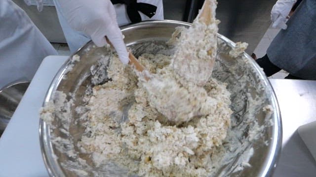 Mixing cream in a large metal bowl with wooden spatula