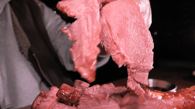 Hand lifting juicy roast turkey leg from cutting board.