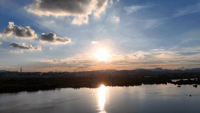 Sunset over a calm river with city skyline