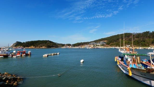 Boats docked in a serene coastal harbor under a clear blue sky