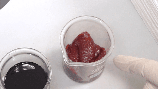 Red paste and black liquid inside beaker