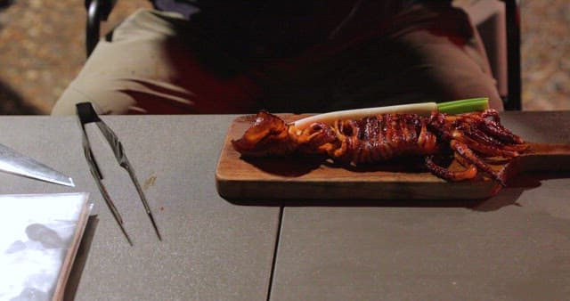 Preparing grilled squid at an outdoor setting