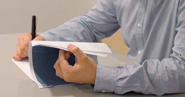 회사 사업 관련 자료에 펜으로 메모하는 사람