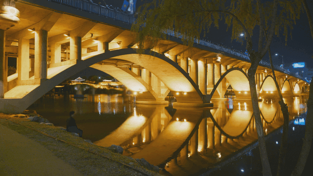 밤에 조용한 강 위의 조명된 다리