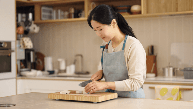Profile of woman cutting tofu in kitchen