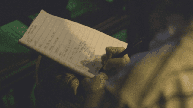 Person writing notes in dark room