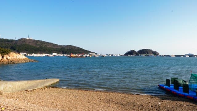 Calm seaside with boats and mountains in the background on a clear day