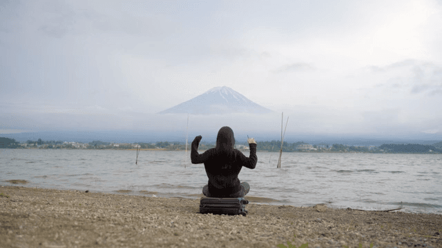 후지산이 보이는 호숫가에 앉아 있는 사람