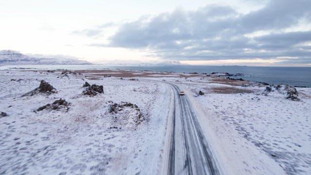 Car driving on a snowy coastal road