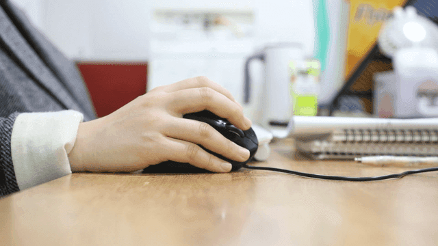 Hand using a computer mouse on a desk