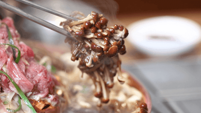 Bulgogi hot pot with beef, chopsticks lifting mushroom