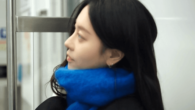 Woman wearing a blue scarf stands up to get off the subway.